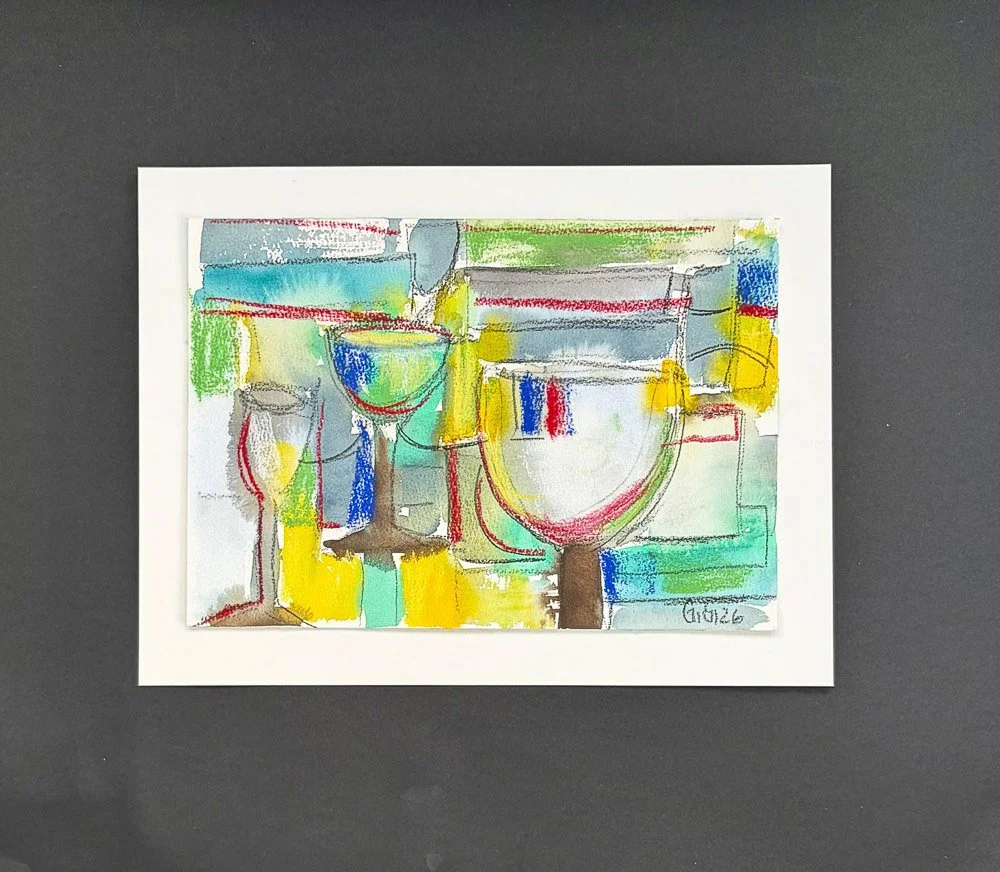 Colorful abstract drawing of glasses and bottles on white paper framed with white border, placed on gray background.