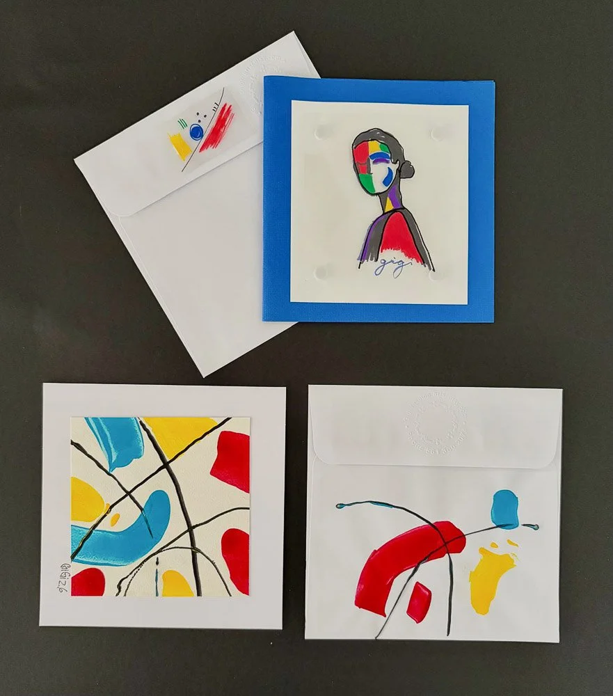 Three pieces of abstract art with colorful shapes and lines. One is a portrait of a woman with a divided face in a blue frame, signed by Gina. The other two are square pieces with abstract patterns in blue, yellow, red, and black lines, one in a whit