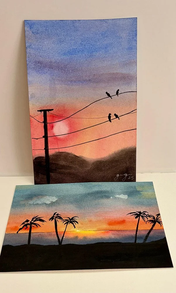 Two watercolor paintings of sunsets, one with birds on power lines against a pink and purple sky, the other with palm trees along the coastline at sunset.