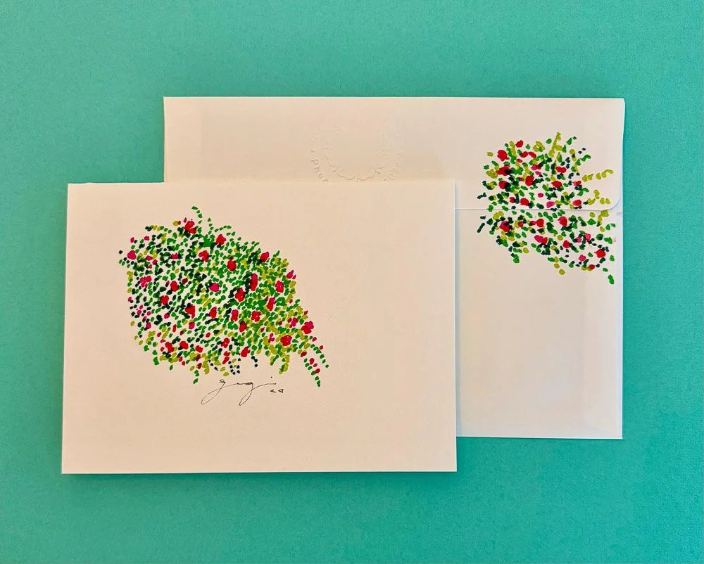 Two white greeting cards with colorful floral designs, laid on a teal surface.