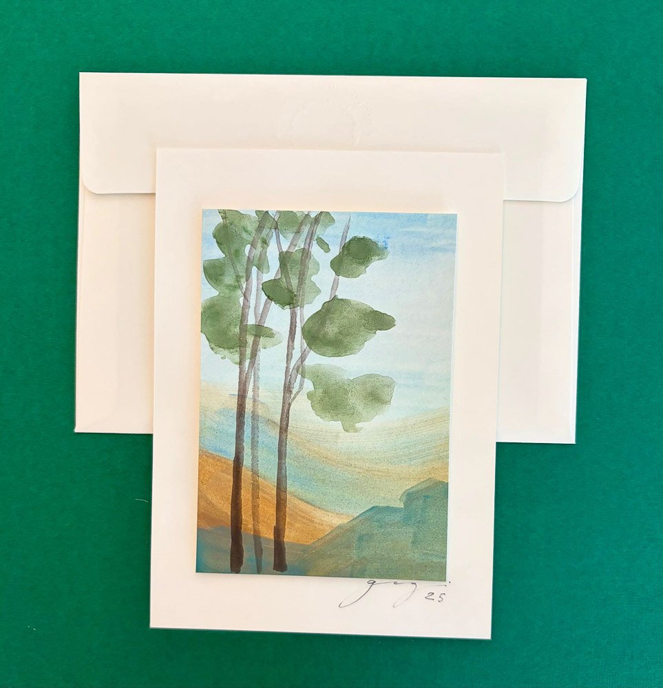 Watercolor painting of three trees with green leaves, set against a background of hills and a blue sky, signed and dated 'J. G. 25'.