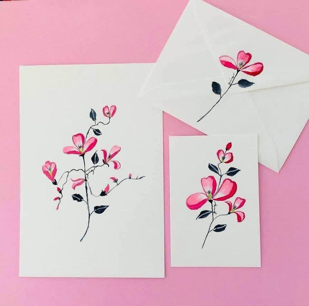 Set of greeting cards with pink floral watercolor designs, one card with a bouquet and an envelope with a matching flower, on a pink background.