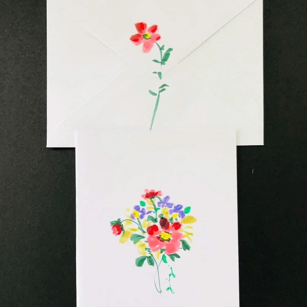 Two pieces of paper with colorful flower drawings, one with a single red flower and the other with a bouquet of various colorful flowers, on a black background.