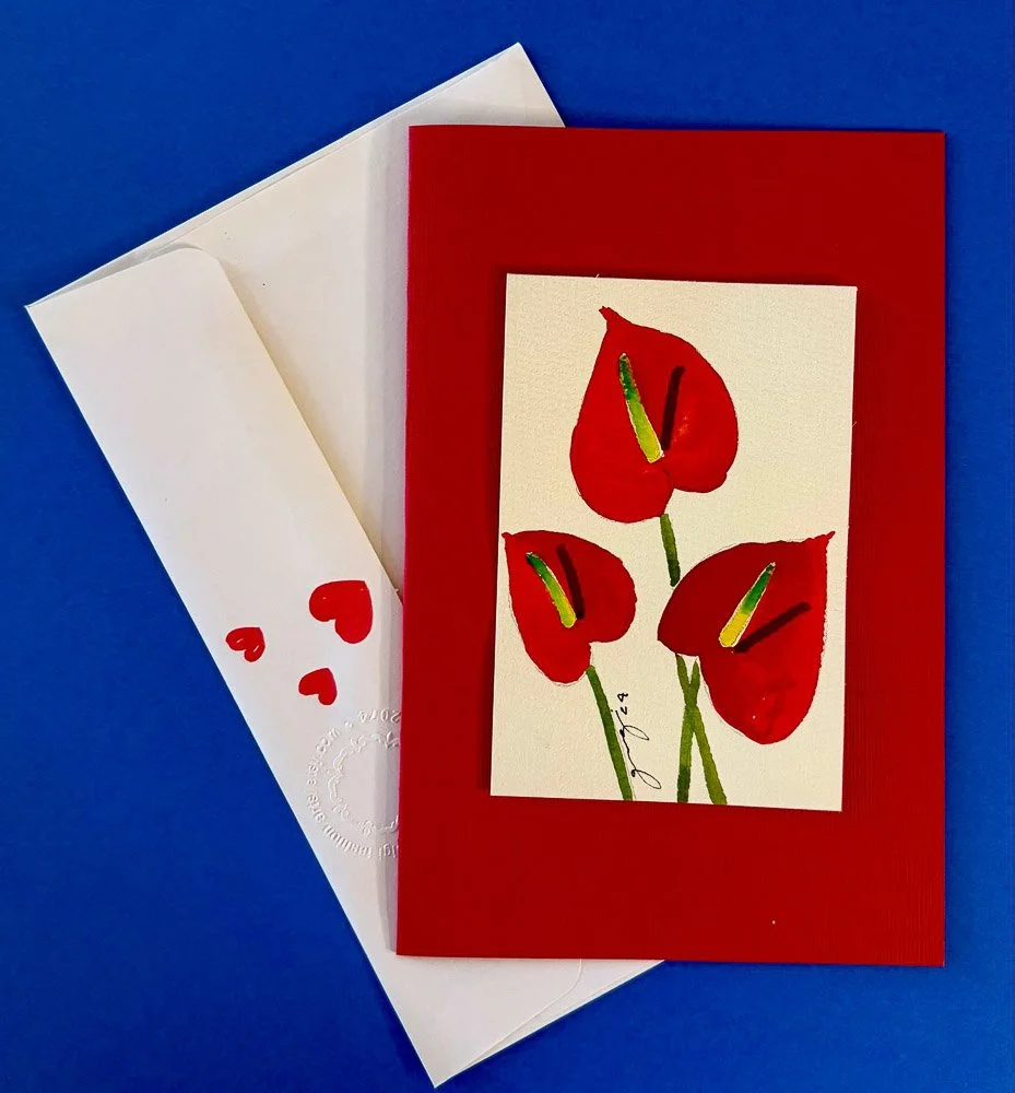 A greeting card with a red border featuring three red flowers with green stems, placed on a blue background.