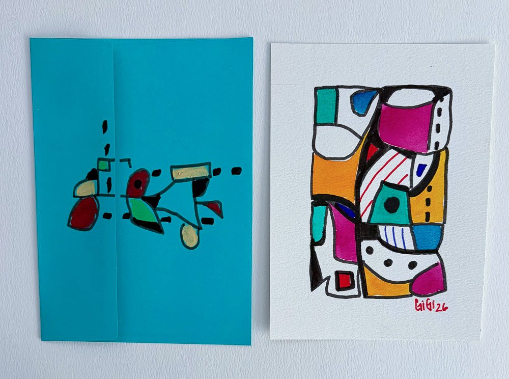 Two abstract paintings on a white wall, one with geometric shapes on a blue background, the other with colorful blocks and black outlines, signed 'Gigi 22'.