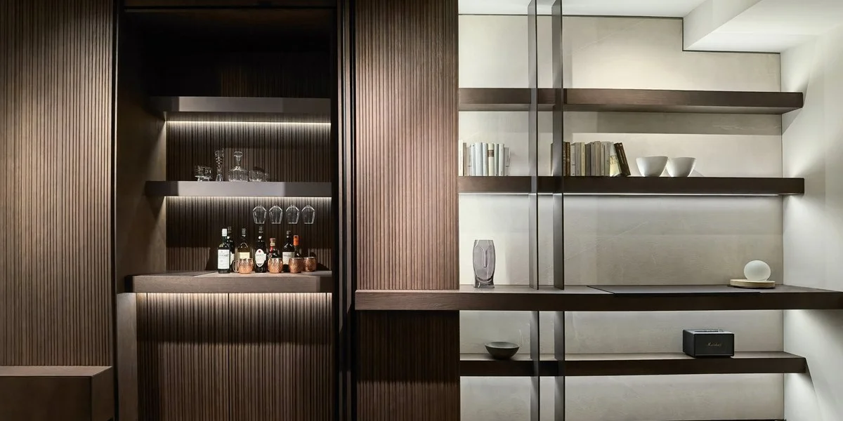 Soggiorno con pareti in legno scuro e scaffali bianchi con oggetti decorativi e libri.