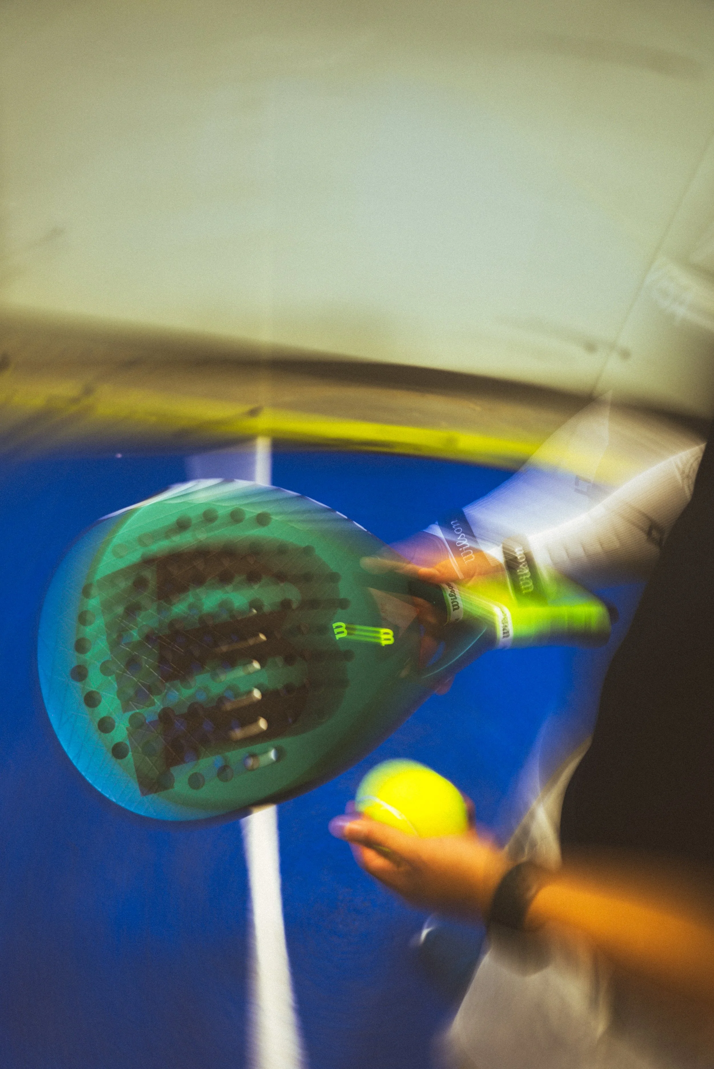 Person holding a yellow tennis ball and a tennis racket on a blue tennis court.