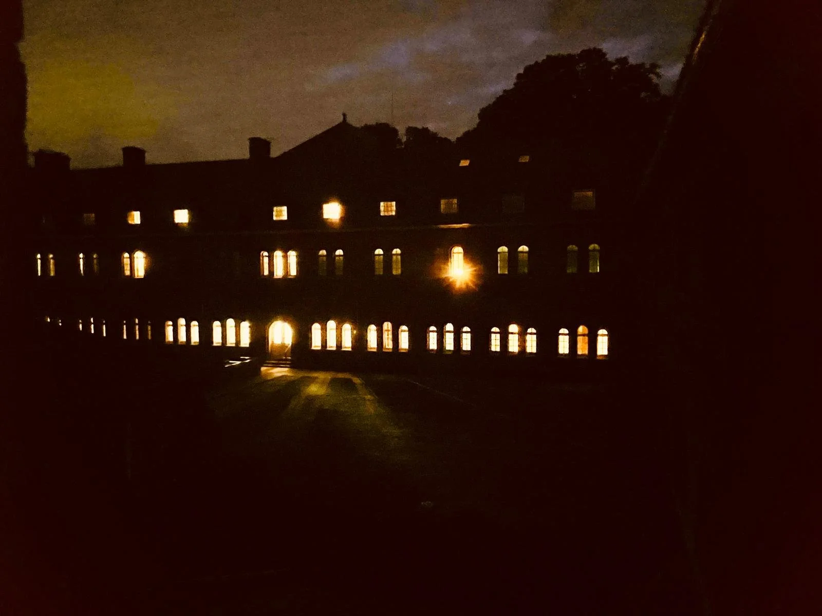 Licht in een donker gebouw met ramen en een deur, nacht.