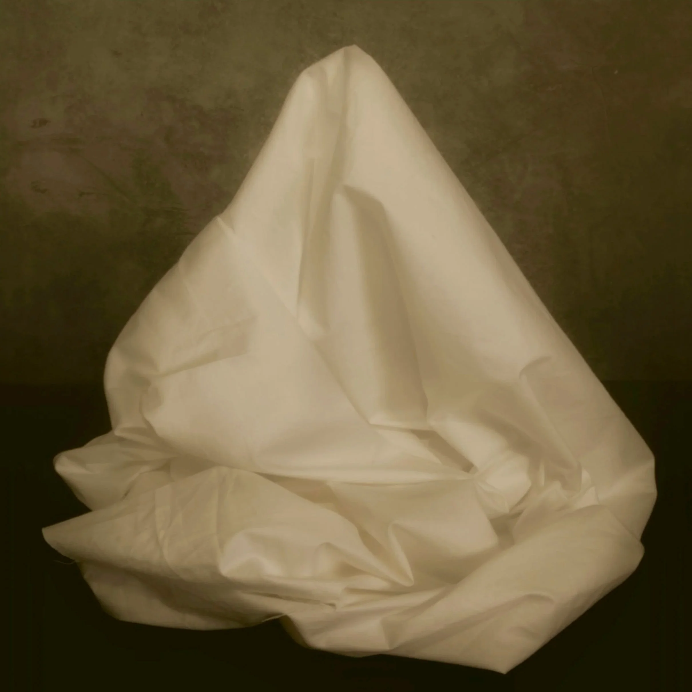 A white cloth or sheet draped over an object or surface, with a dark background.
