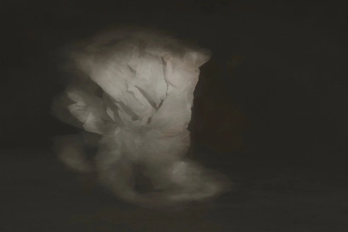 A dark cave with an opening showing a glow of light and a reflective water surface.