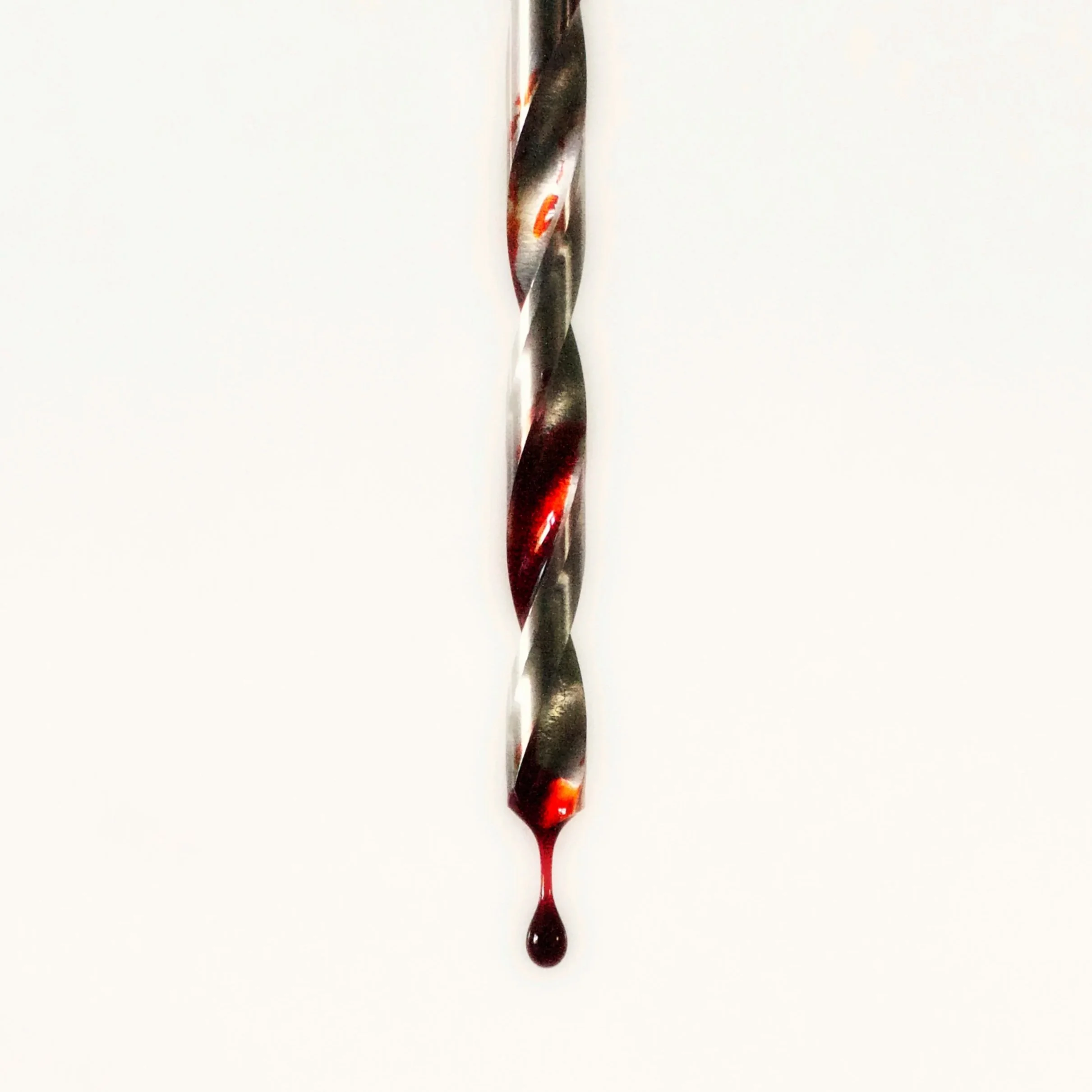 A metal knife with a twisted design has red and black paint splattered on its surface, with some red paint dripping from the tip, set against a plain white background.