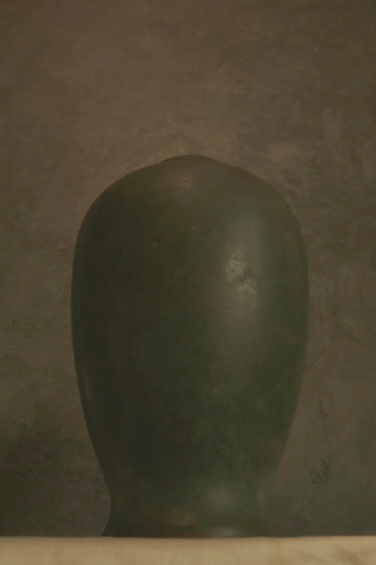 A close-up of a dark, rounded object against a dark background with a light source reflecting off its surface.