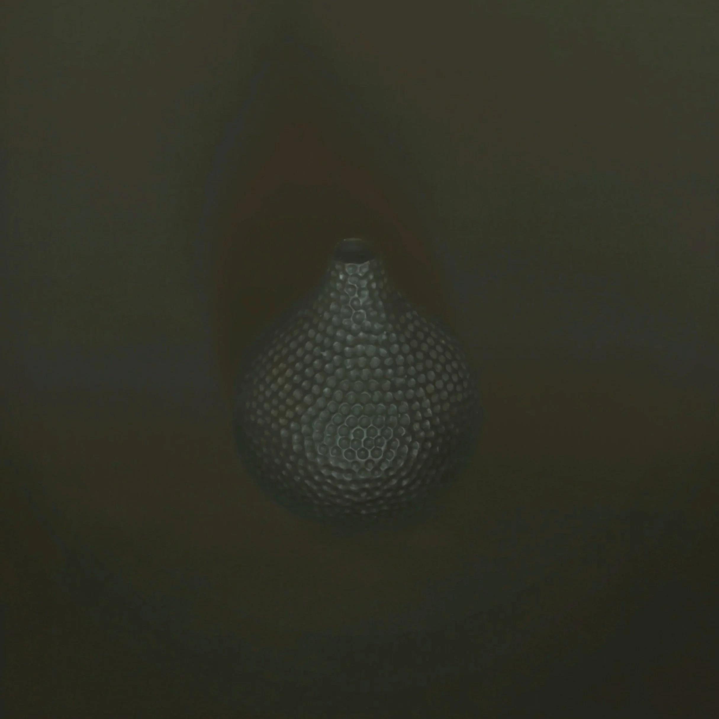 A dark, blurred image with a pattern of hexagons and a small circular object near the bottom center.