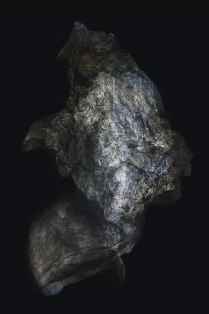 A crumpled piece of gray and black textured material against a black background.