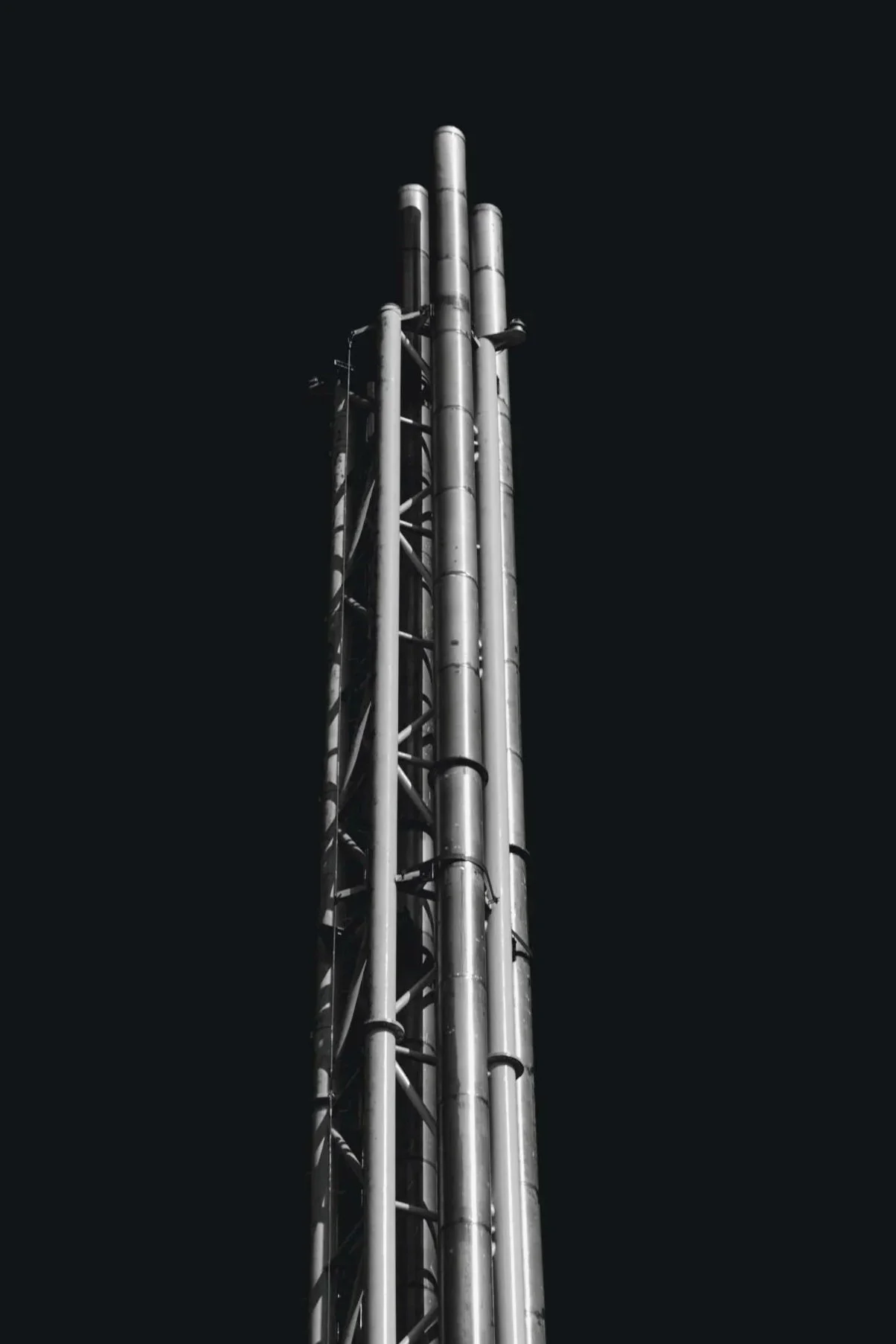 A tall metal industrial structure, likely a chimney or exhaust pipe, against a dark night sky.
