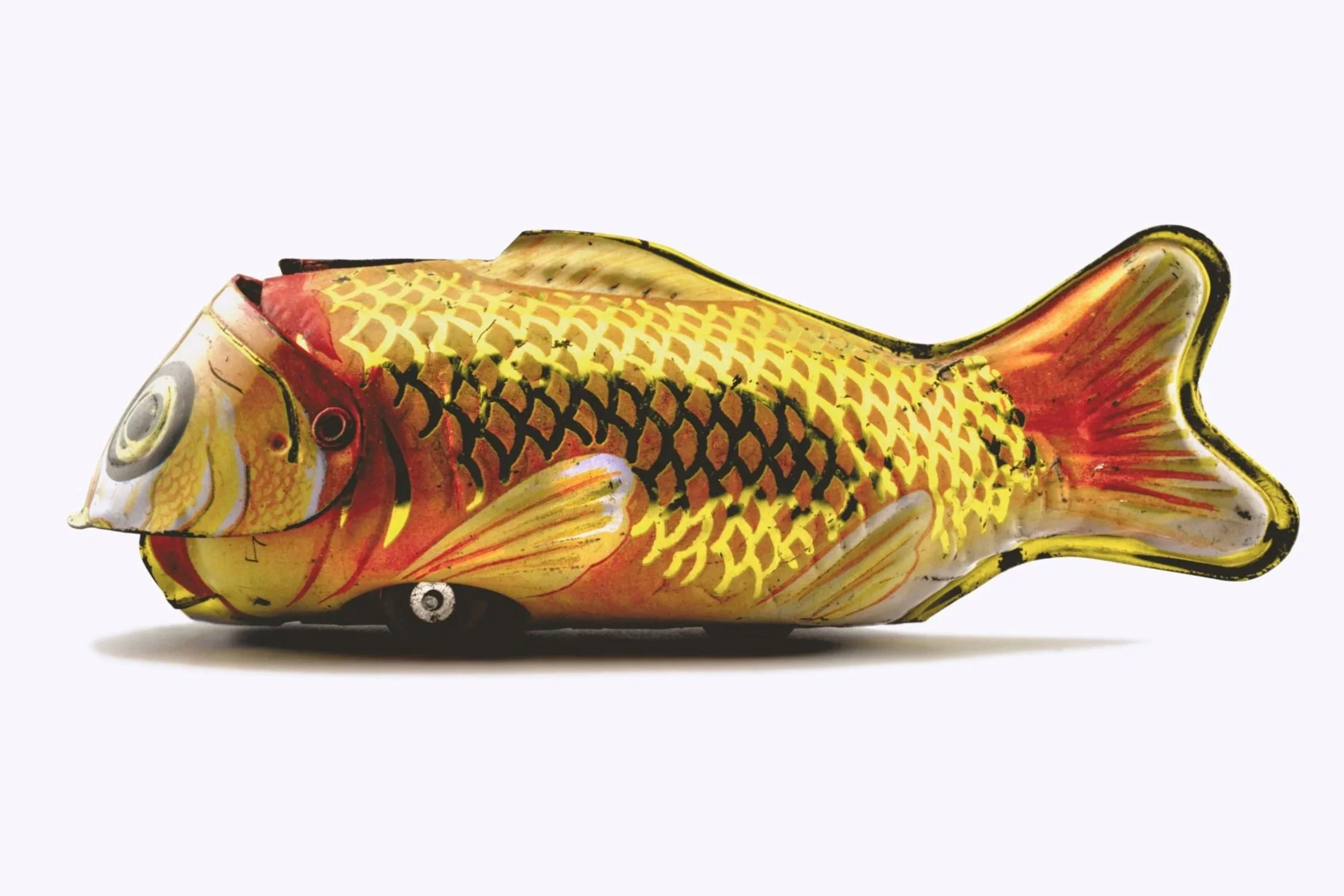 Colorful fish-shaped ceramic sculpture with yellow, orange, and black scales, and a fish eye, on a plain light background.