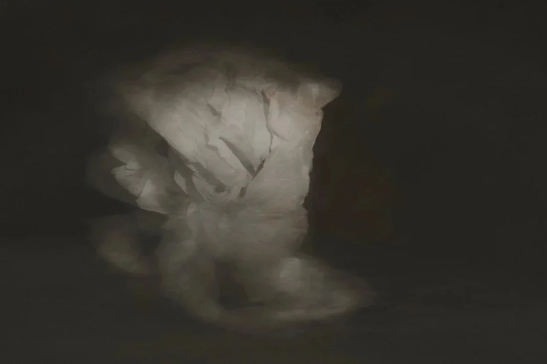 Dark cave interior with large illuminated rock formation and a body of water reflecting the rock