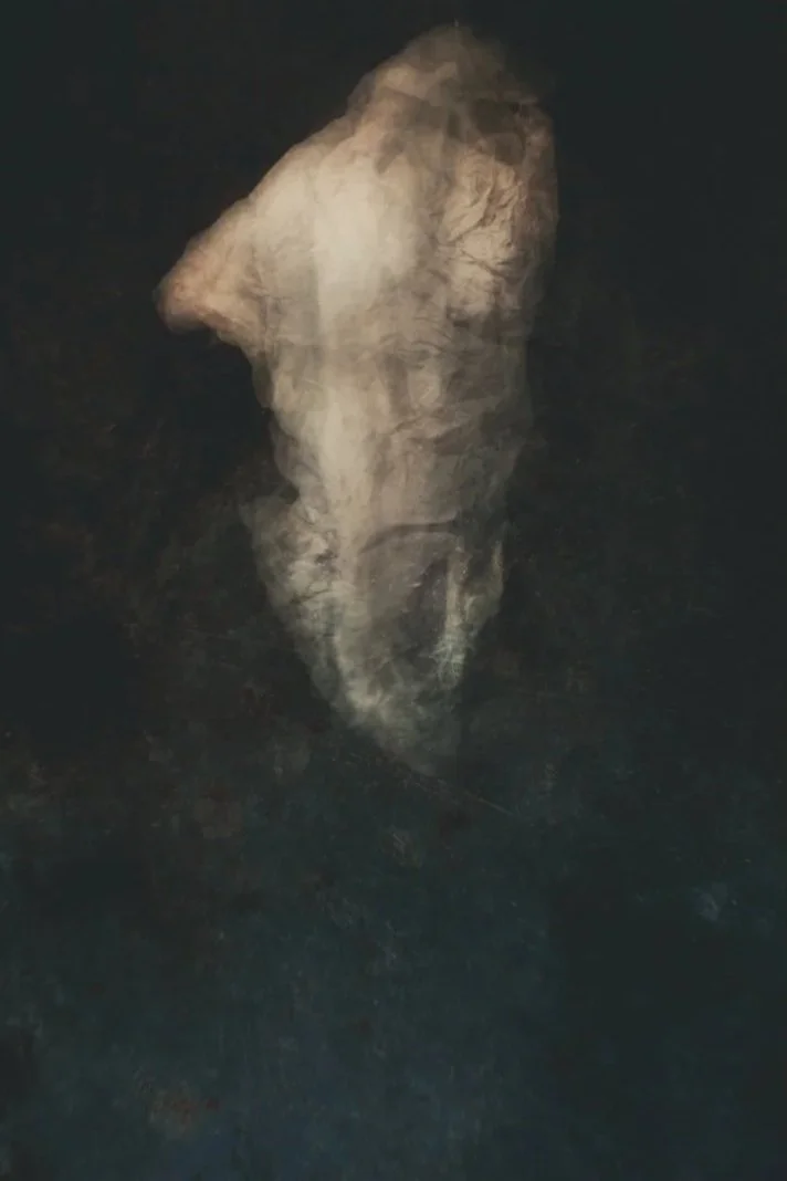 Blurry and dark abstract image resembling a human face in profile view, with a dark background.