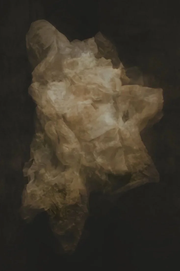 A beige and light brown abstract rock formation or sculpture set against a black background.