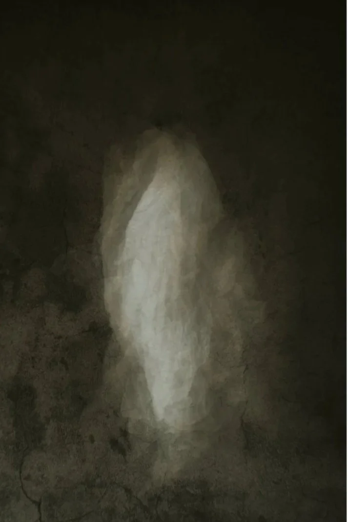 A blurry, ghostly figure of a person with long hair, dressed in white, standing against a dark background.