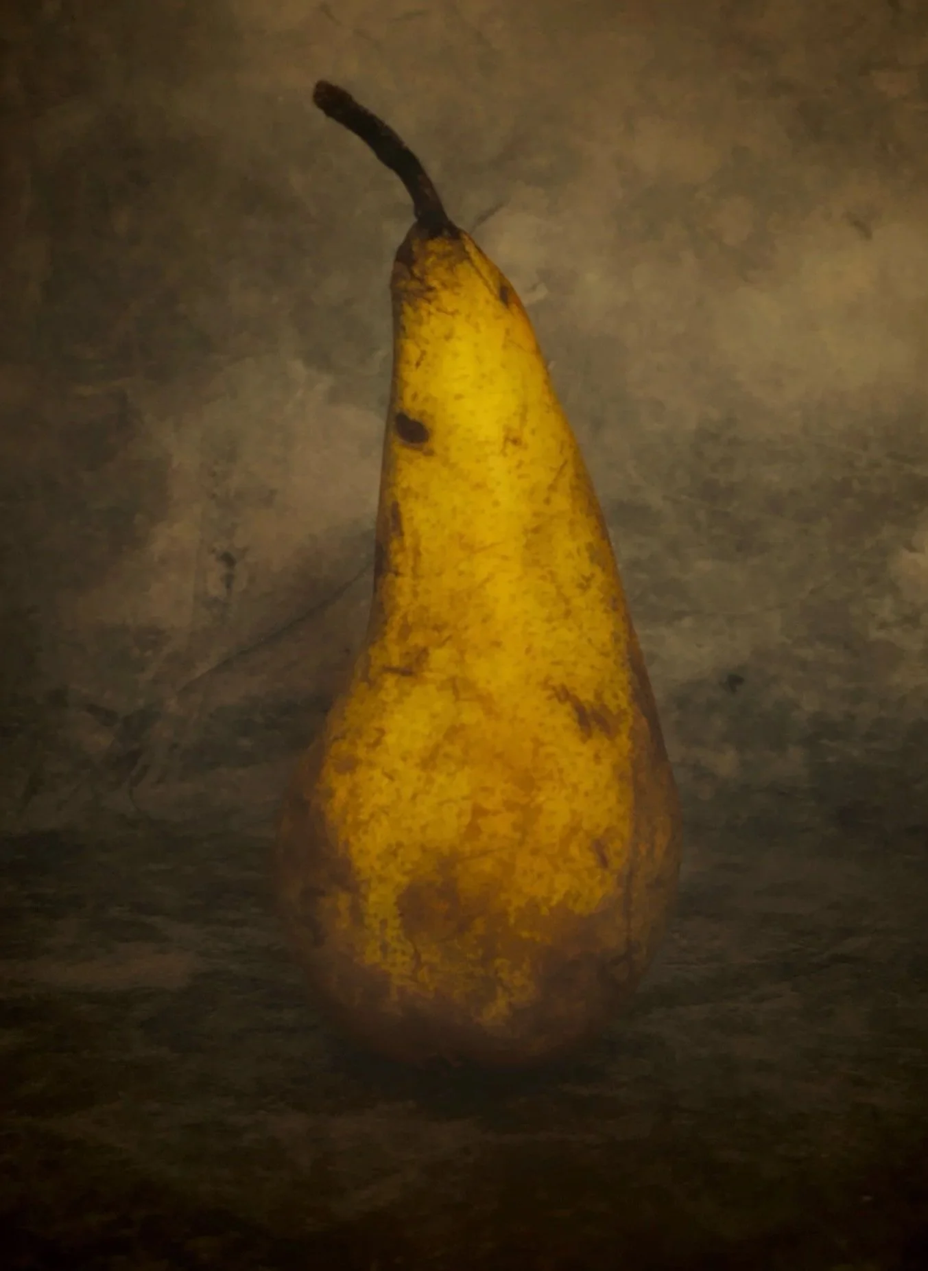 A yellow banana with a partially blackened peel, placed on a dark surface against a dark background.