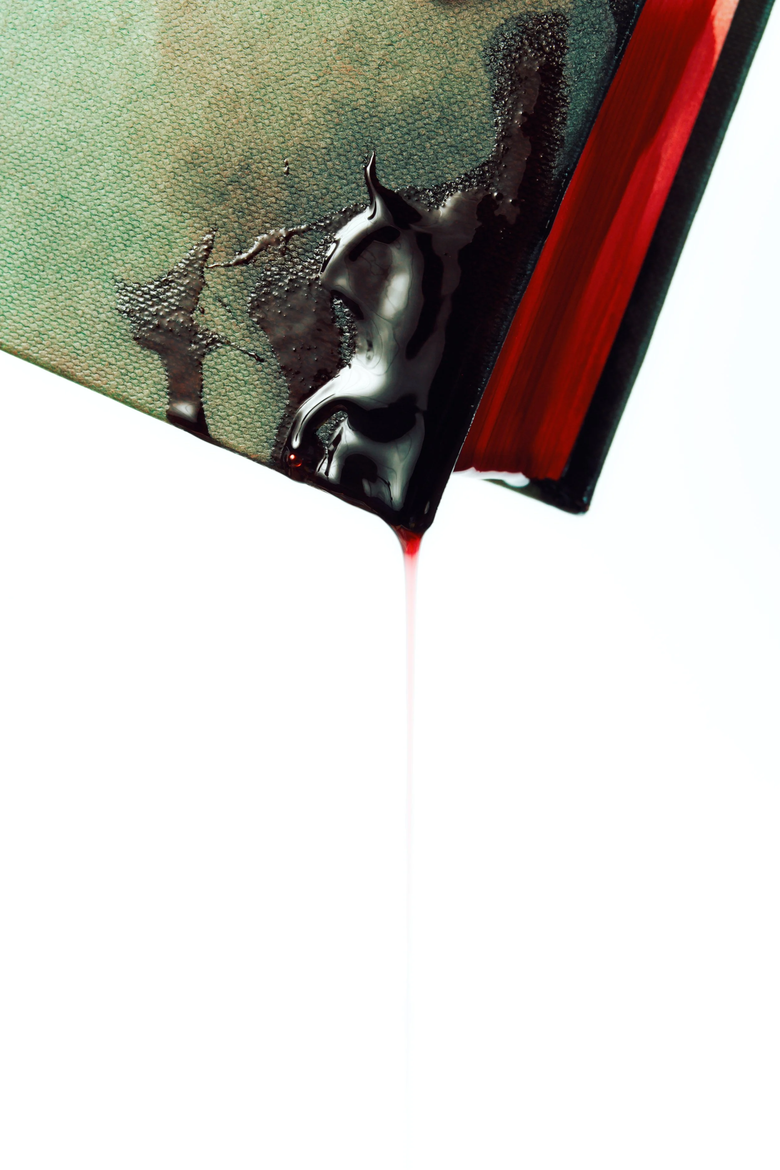 Close-up of a book with black ink spilling from the pages, creating a dripping effect.