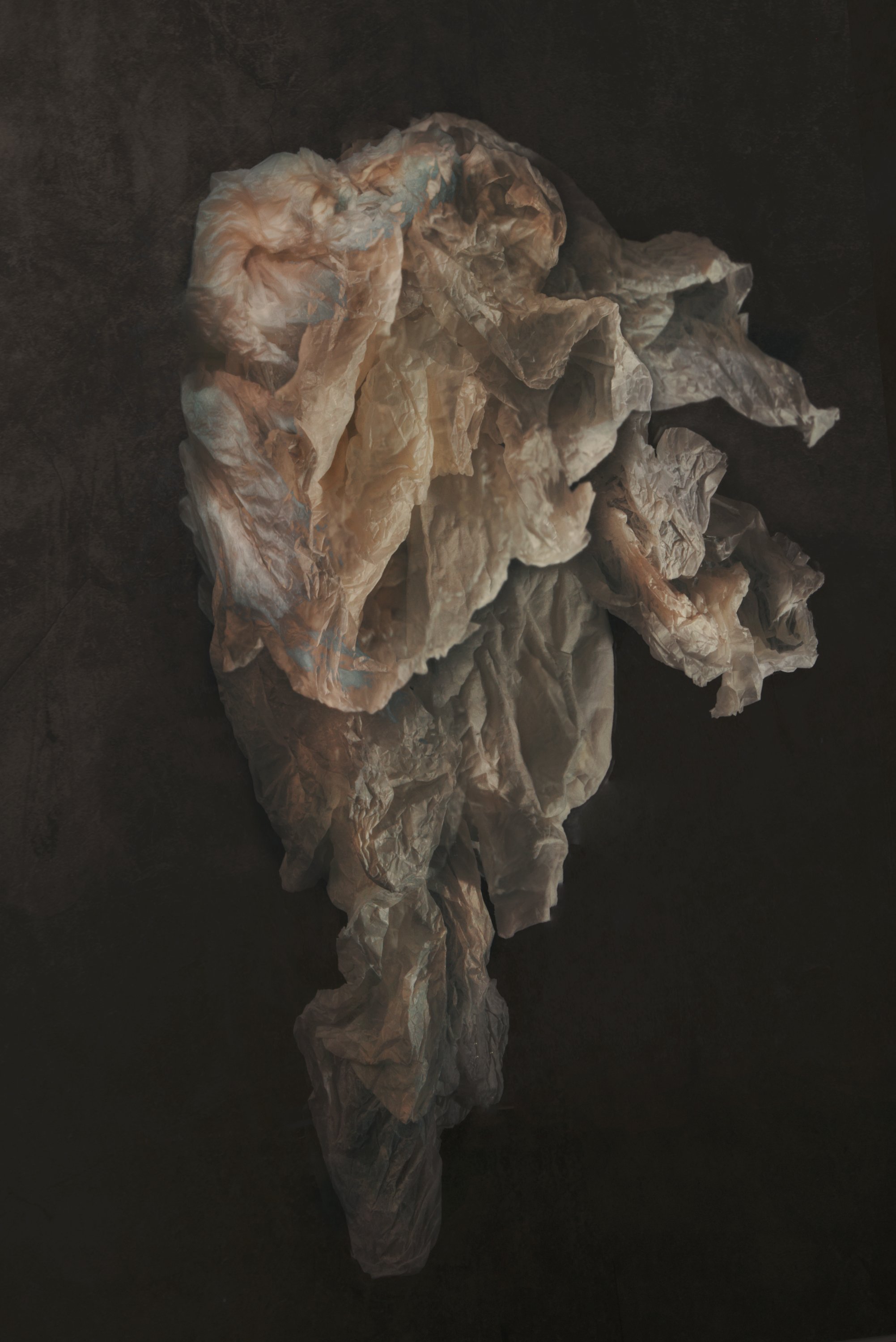 Crumpled used tissue paper on a dark surface.
