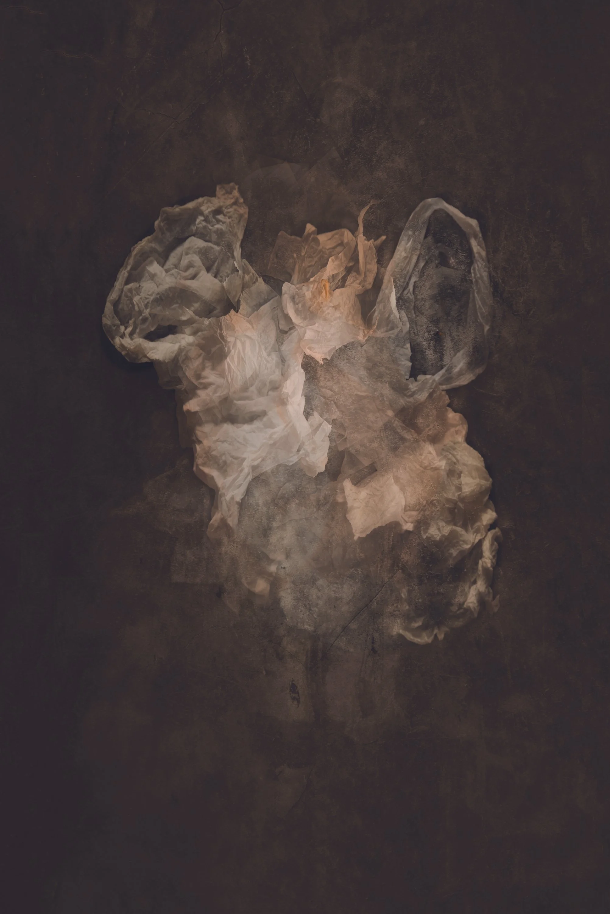 A pile of crumpled, white and beige tissues or paper on a dark surface.