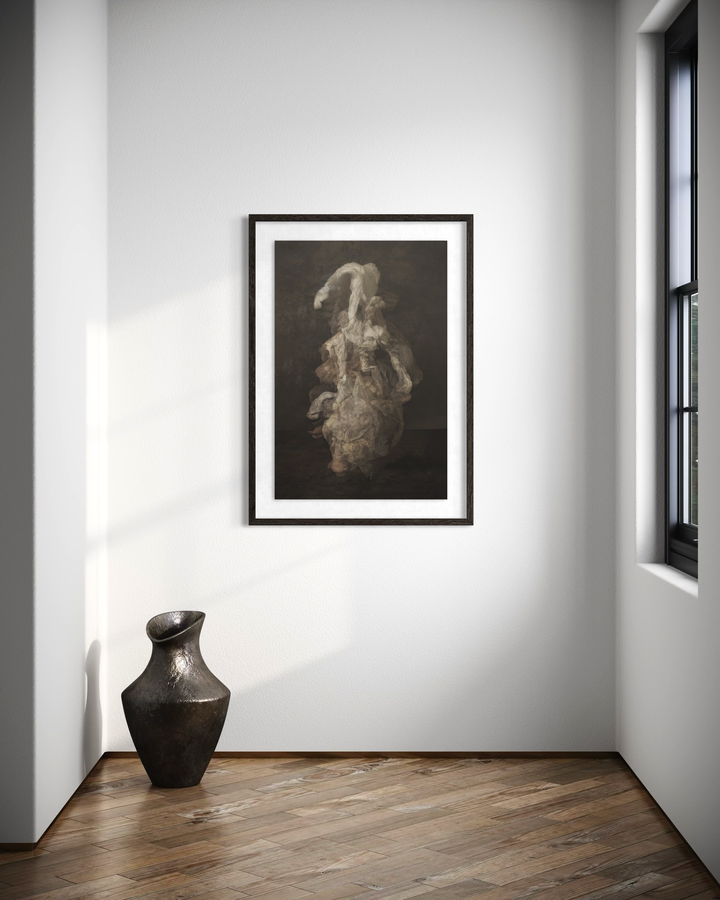 A framed abstract painting hanging on a white wall in a corner of a room next to black window frame. A tall, black ceramic vase stands on a wooden floor in the foreground.