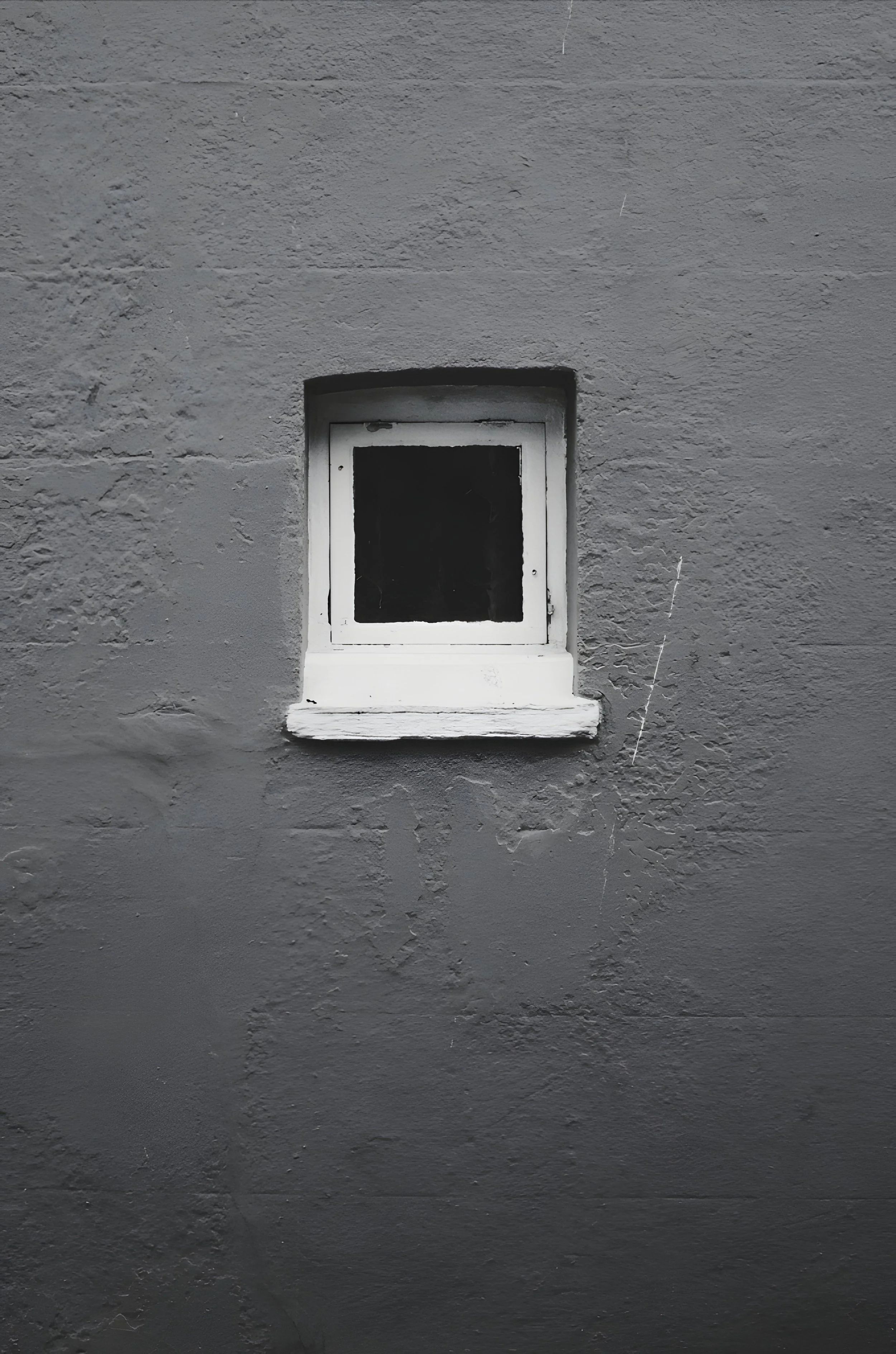 Small, square window set into a dark, textured wall.