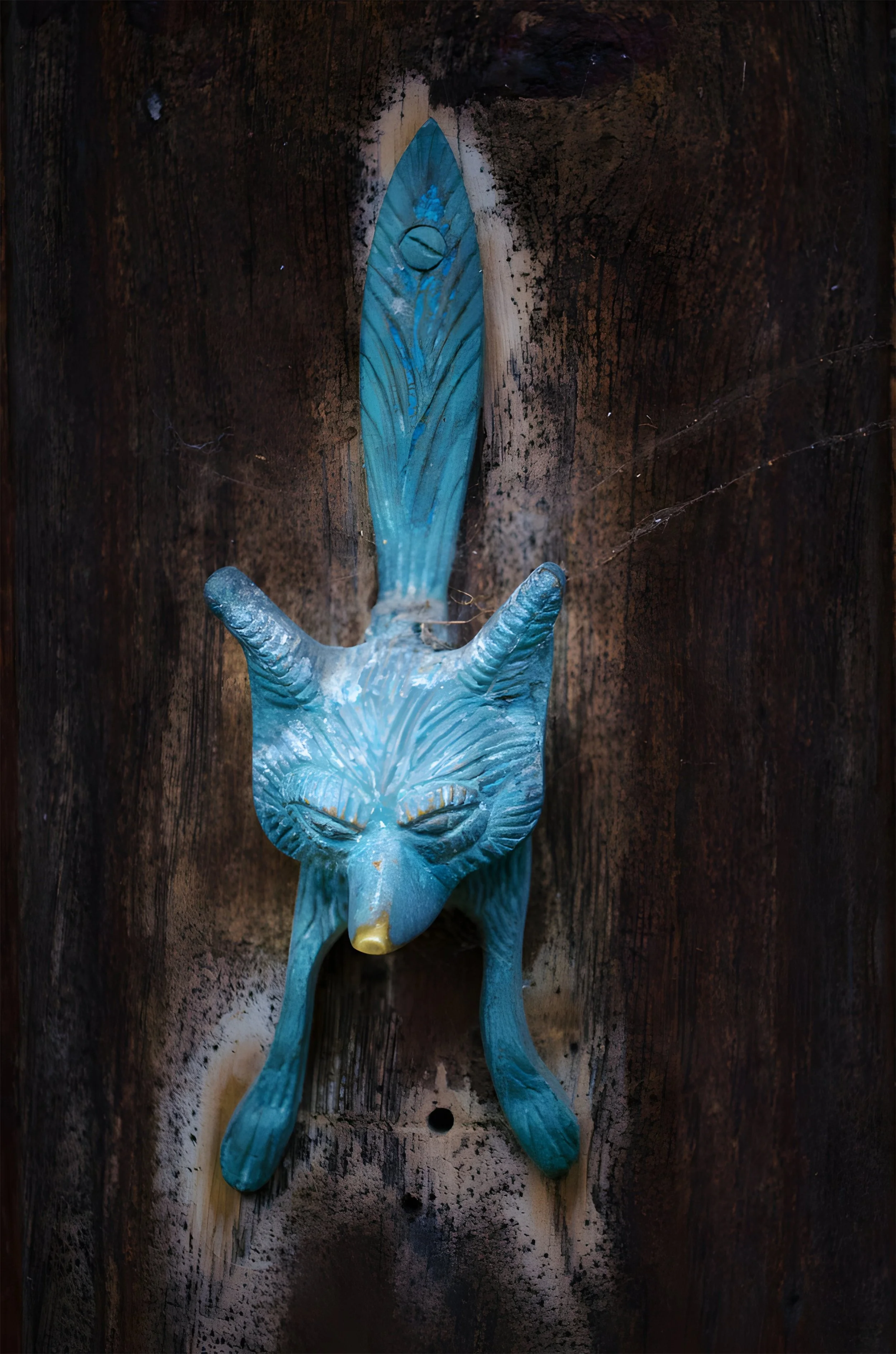 A decorative wall hook shaped like a fox with a blue body, hanging on a dark wooden surface.
