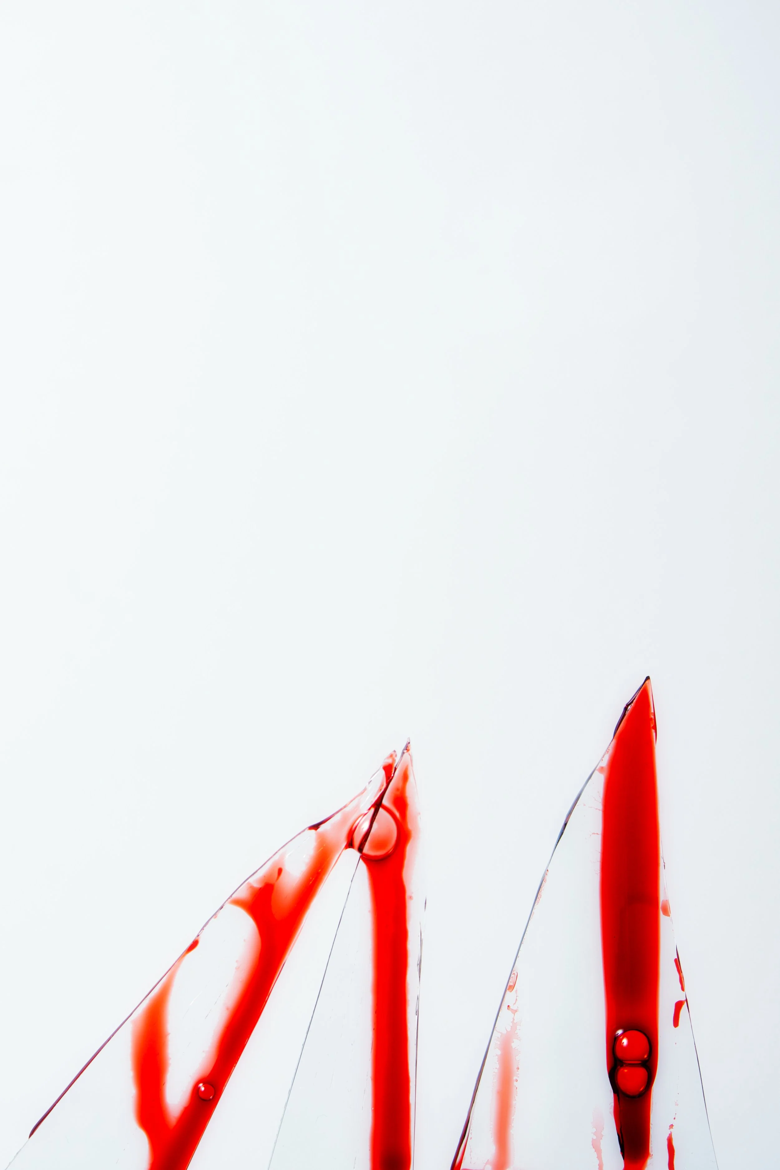 Red paint splattered on a white surface with thick drops and thin streaks.