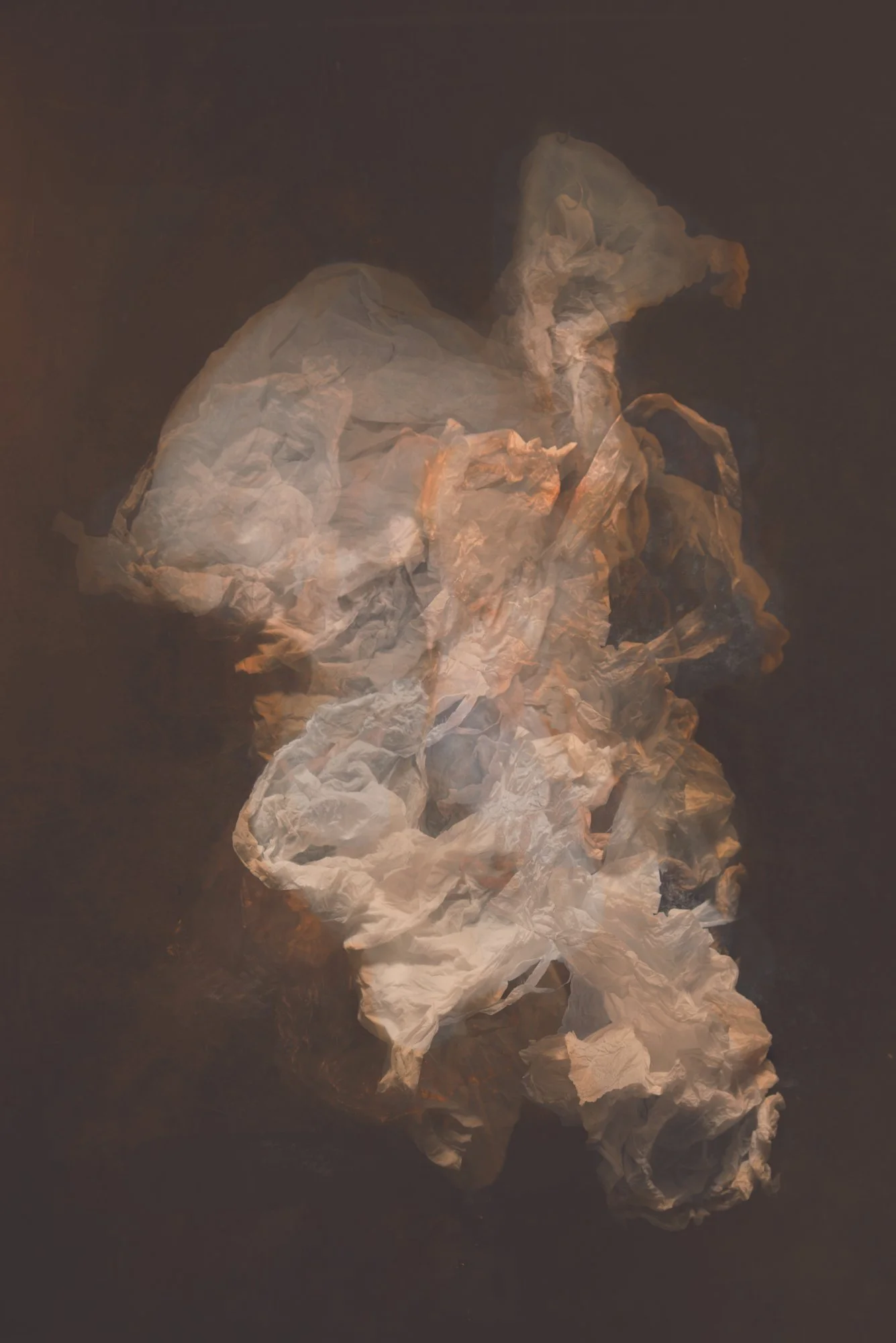 A figure made of crumpled paper resembling a seated person in profile, against a dark background.