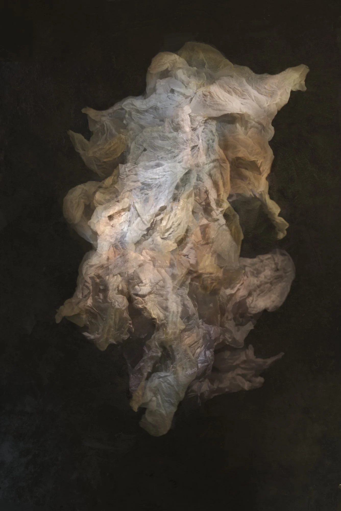A pile of crumpled, off-white paper on a dark surface.