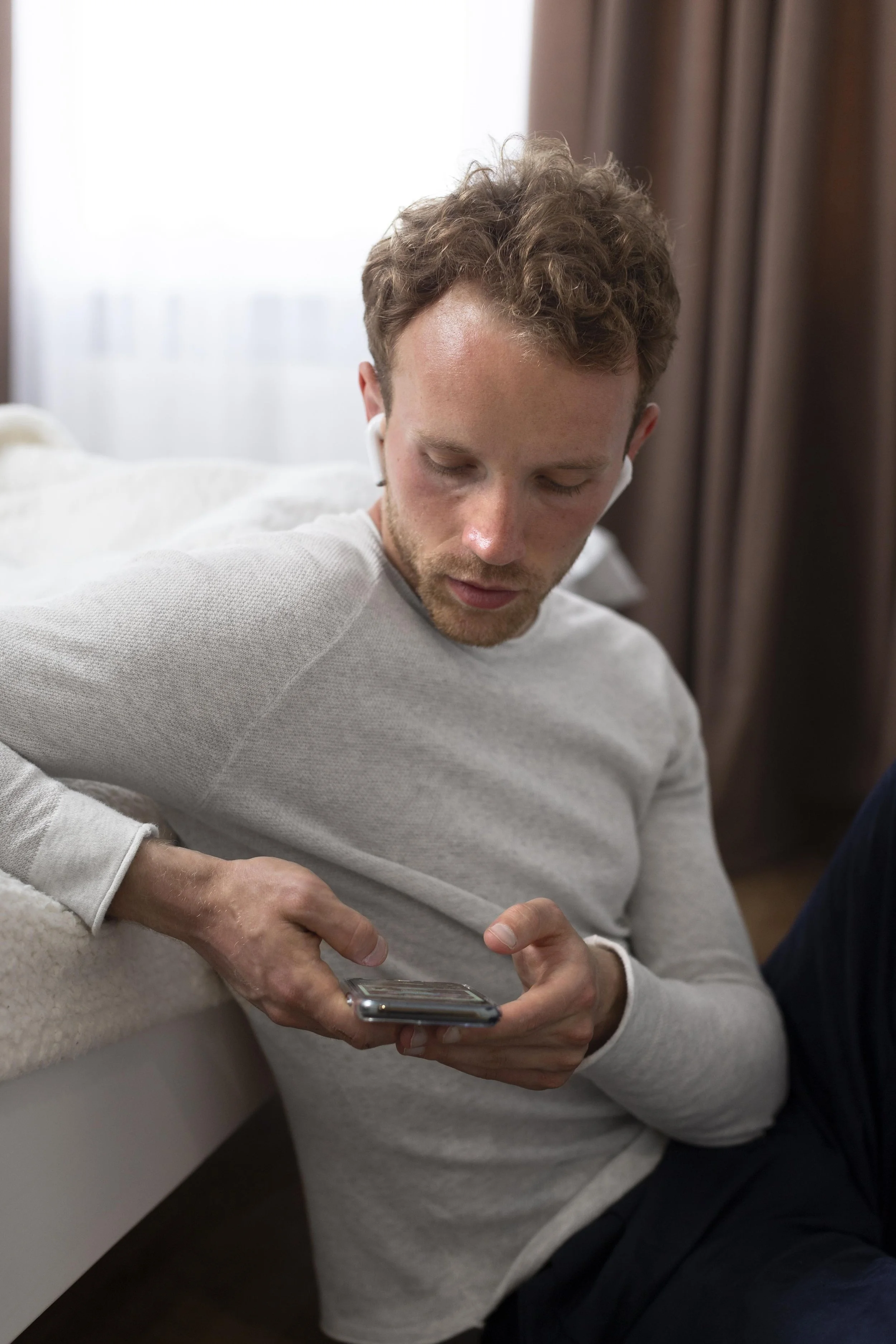 Individual listening on a smartphone with earphones for remote therapy support