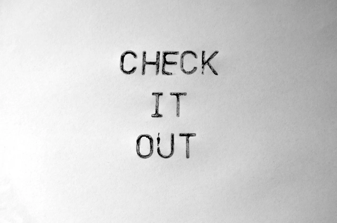Schwarzer Stempel mit den Worten 'CHECK IT OUT' auf weißem Hintergrund.