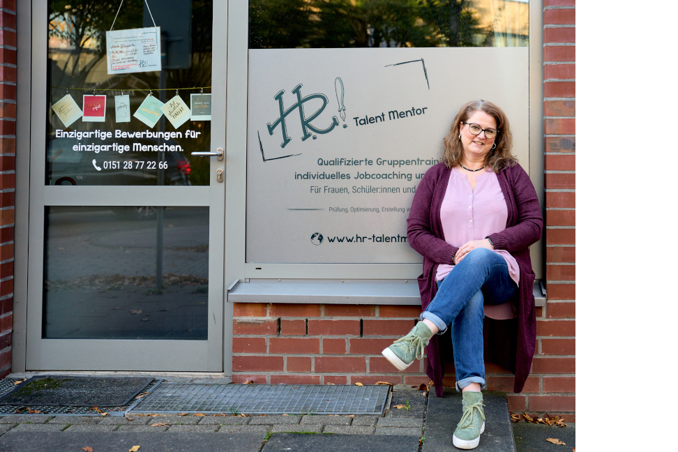 HR-TalentMentor-Laden Seehofallee. Heike Rönsberg sitzt vor dem Schaufenster ihres Ladens.