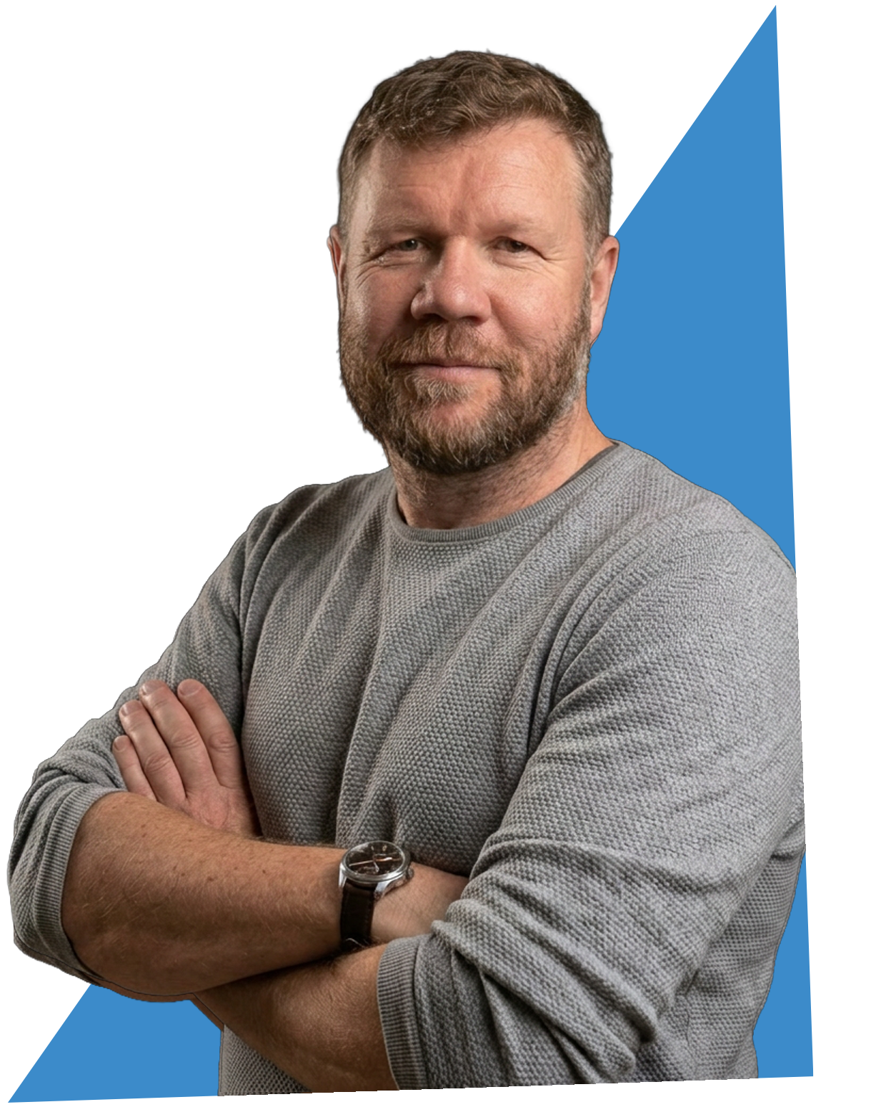 A middle-aged man with a beard and short hair, wearing a gray sweater and a wristwatch, standing with arms crossed against a black background with a blue arrow pointing upward behind him.
