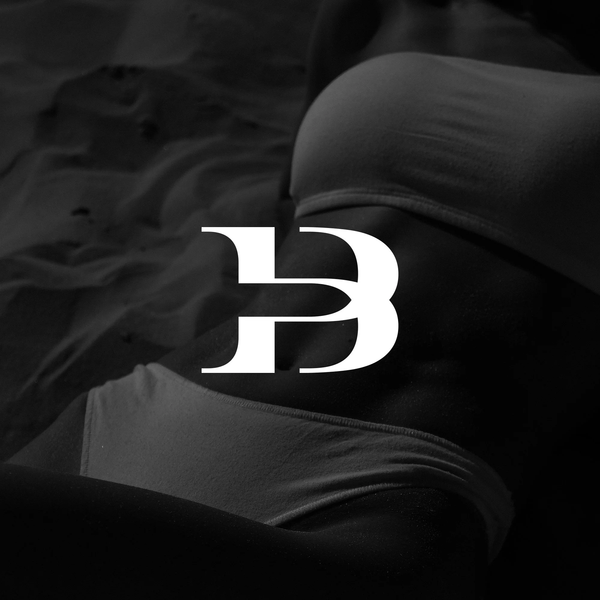 Schwarzes und weißes Bild mit Sport-BH und Sand, überlagert mit einer großen weißen 'B' und der Zahl '3'.