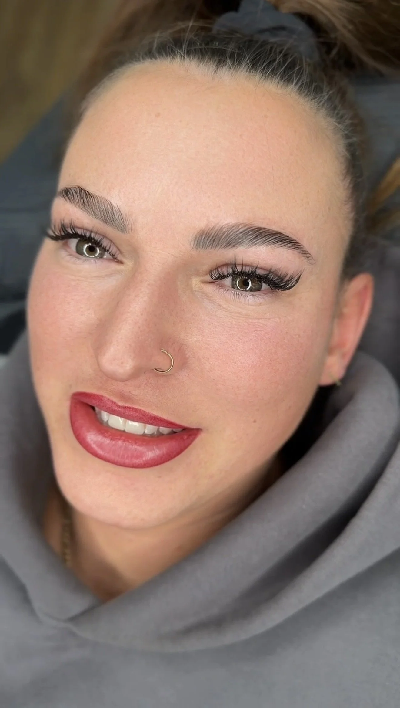 Nahaufnahme eines lachenden Mädchens mit braunen Haaren, das auf dem Rücken liegt.