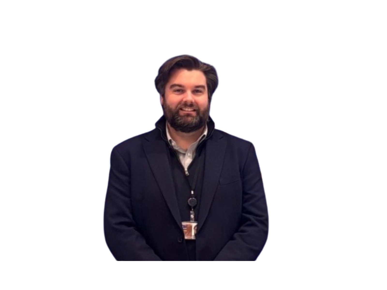 A man with brown hair and a beard, wearing a dark suit and a lanyard with a badge, smiling at the camera.