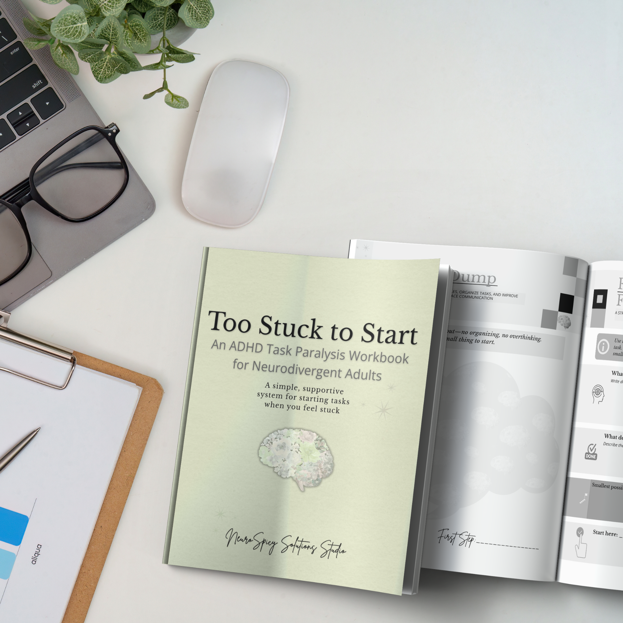 A white desk with a laptop, black glasses, a potted plant with green leaves, a closed book titled 'Too Stuck to Start' with a hydrangea flower on the cover, and an open notebook.