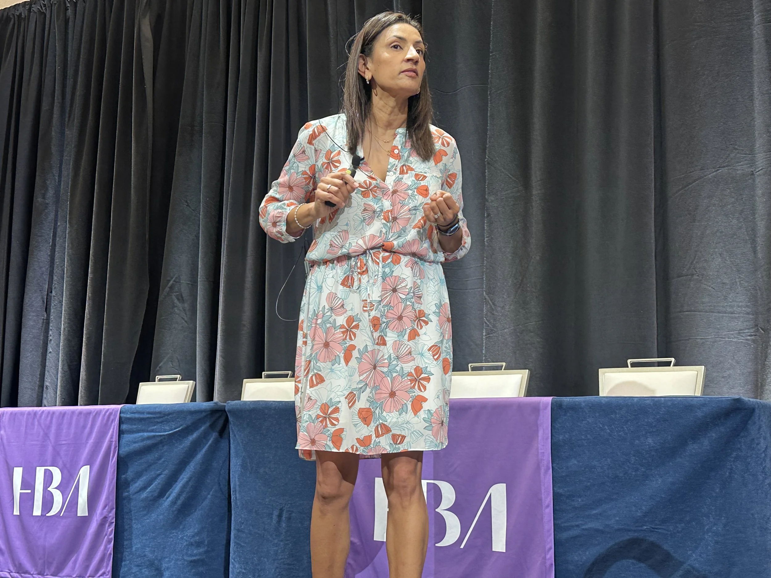 Poornima speaking on conference stage.
