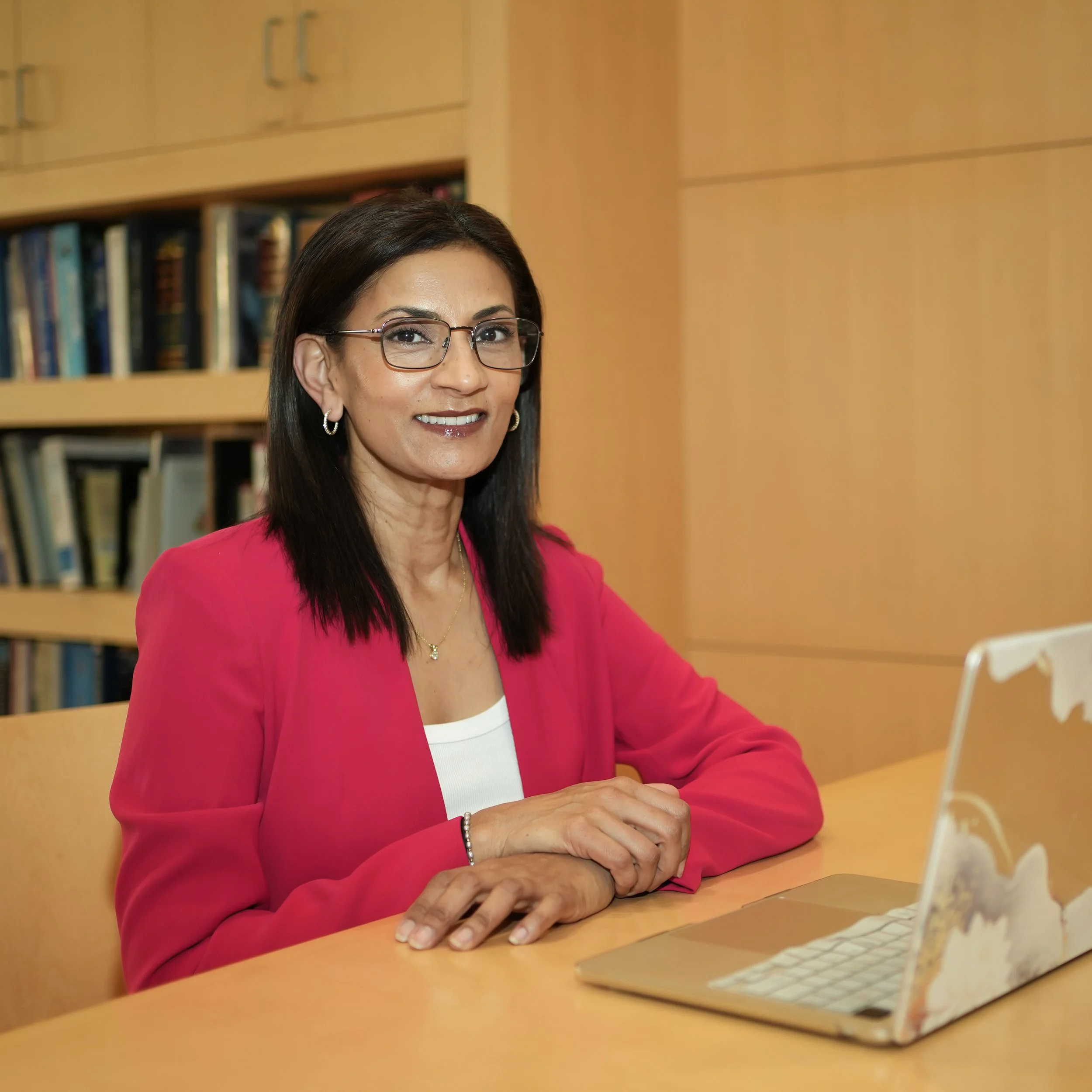 Poornima professional headshot - library, glasses.