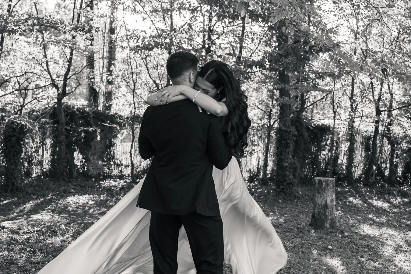 Un couple danse en plein air dans une forêt, en noir et blanc, avec la femme en robe longue et le homme en costume