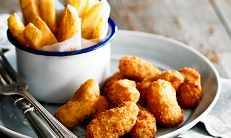 Fried chicken nuggets and French fries in a bowl and on a plate.