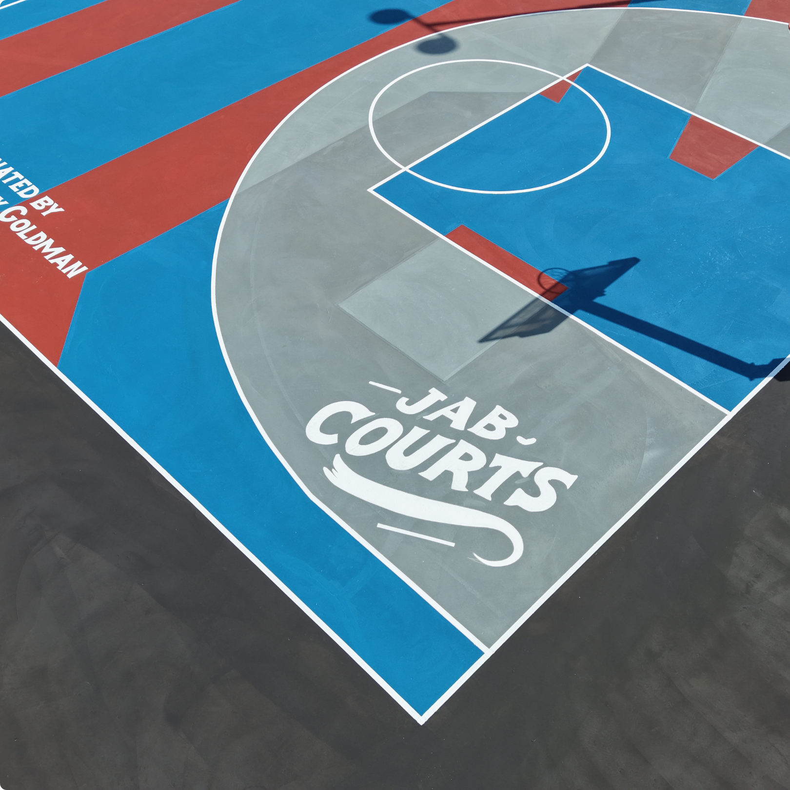 JAB Courts renovated outdoor basketball court with colorful blue, red, and gray design promoting youth community impact