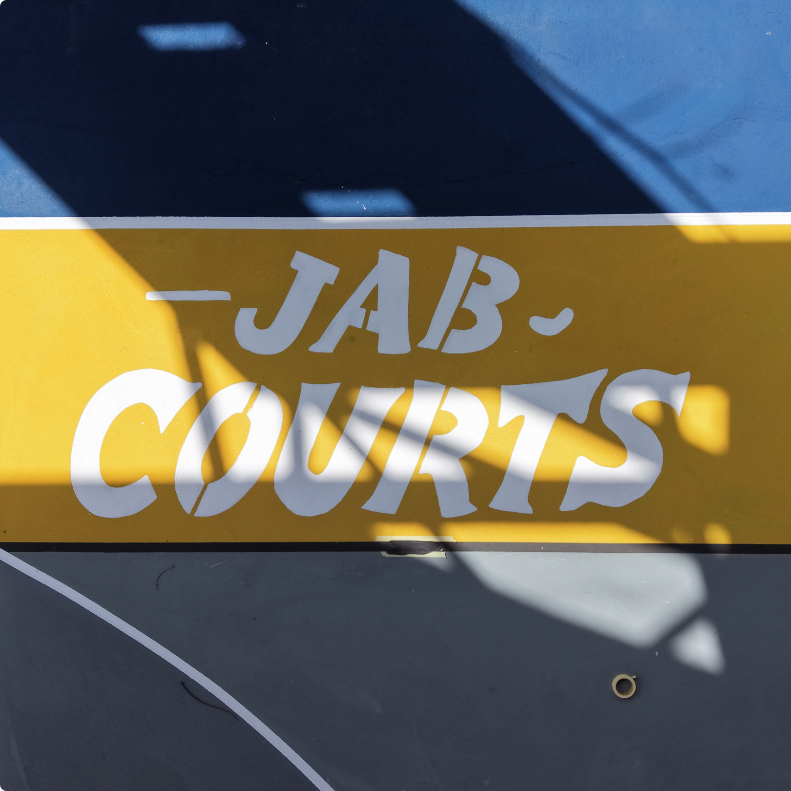 JAB Courts logo painted on basketball court surface representing community basketball court renovation initiative
