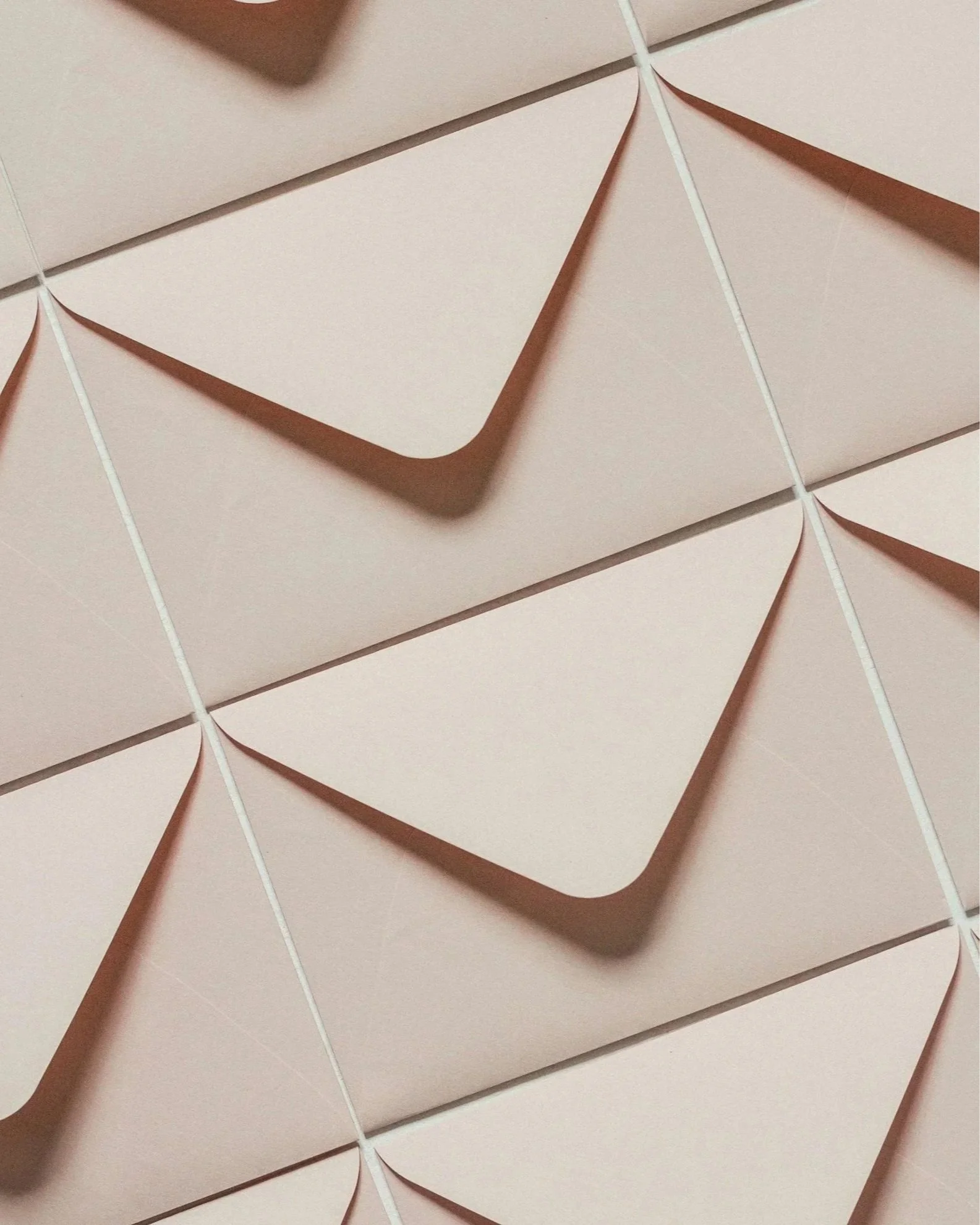 Close-up of pink rectangular boxes with triangular seals on the top, hanging from white strings, arranged in a grid pattern.