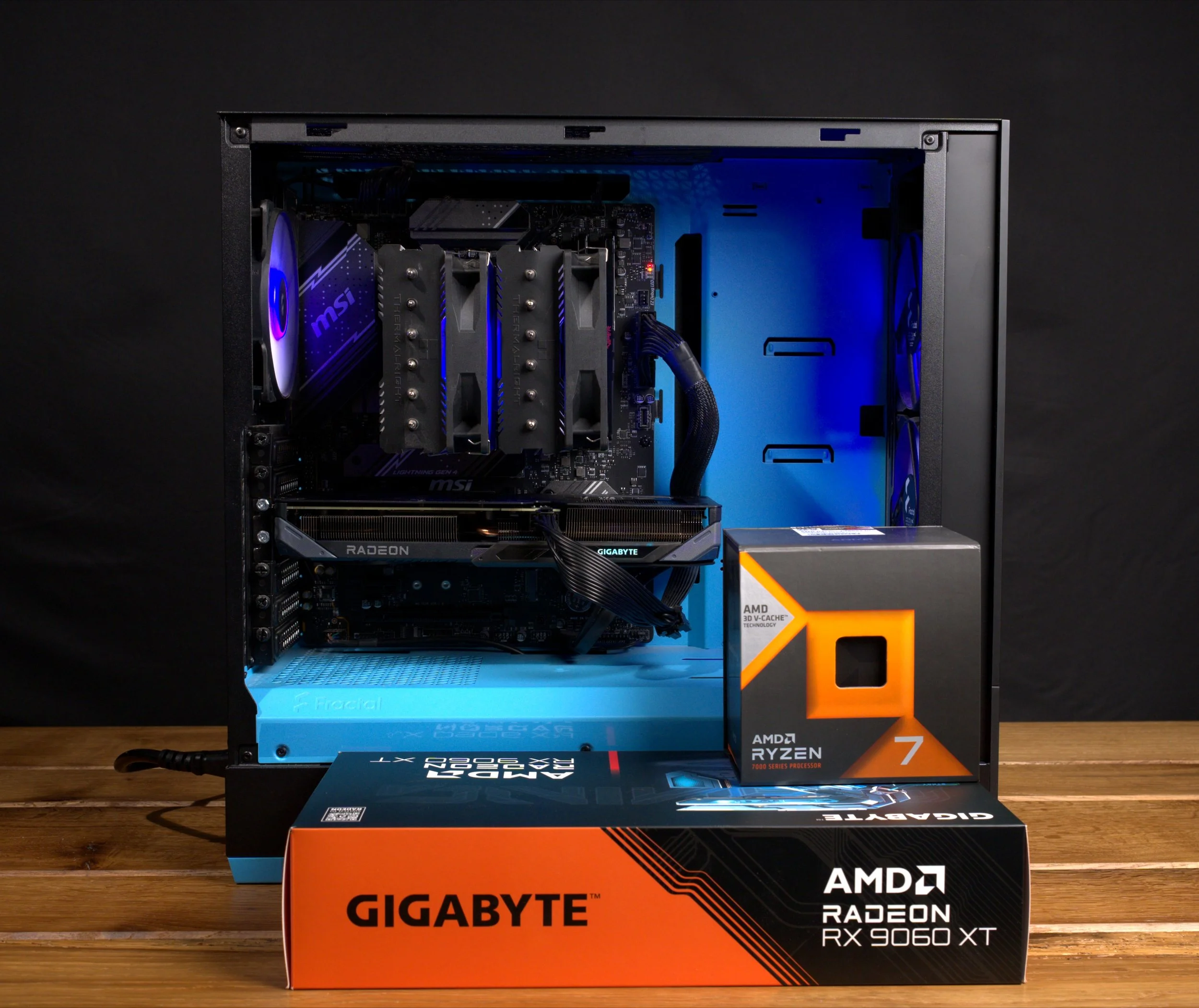 Un ordinateur de bureau monté avec une carte graphique Radeon, refroidissement par air, dans un boîtier avec éclairage bleu, avec une boîte de processeur Ryzen 7 d'AMD et une boîte de carte graphique Gigabyte à l'avant.